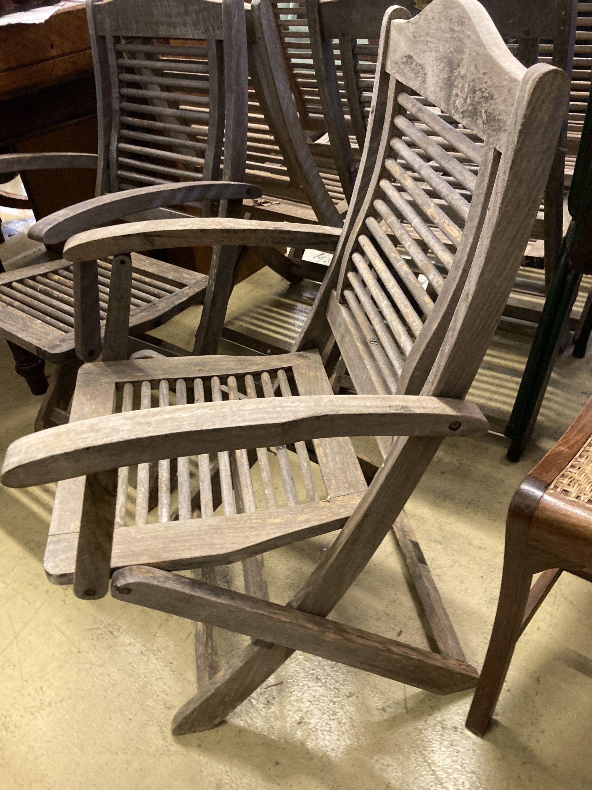 A set of six weathered teak folding garden chairs, two with arms